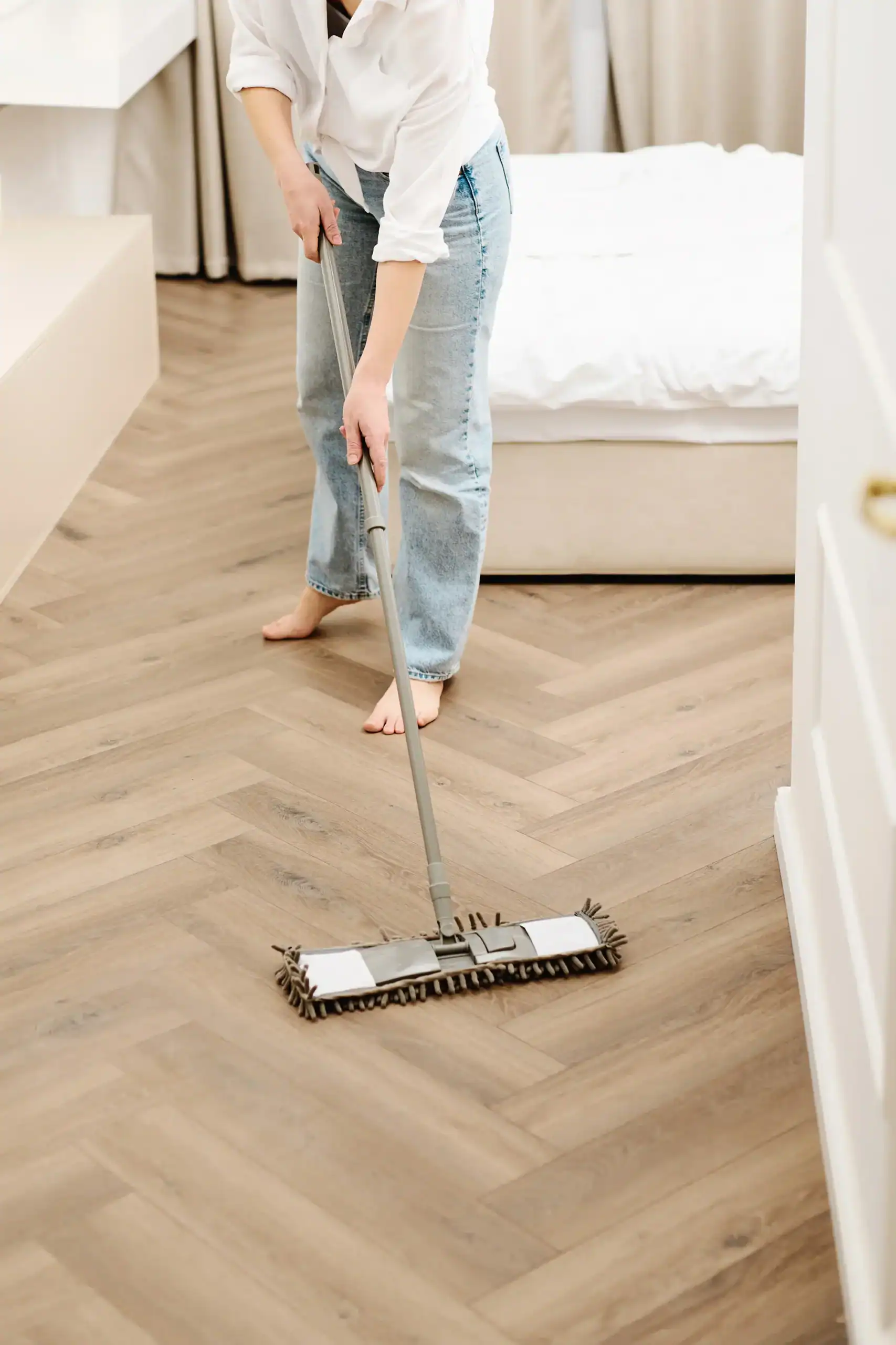 Microfiber flat mop on a herringbone hardwood floor, freshly cleaned with a natural diy floor cleaner