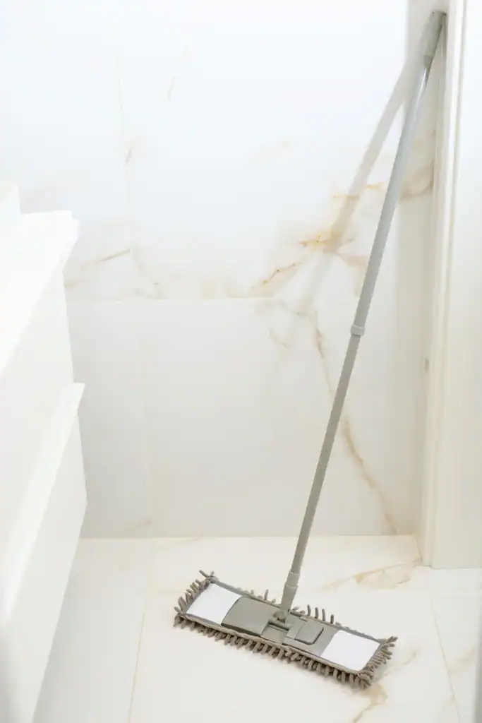 Flat microfiber mop resting on a freshly mopped white marble tile floor, ready for a diy floor cleaner