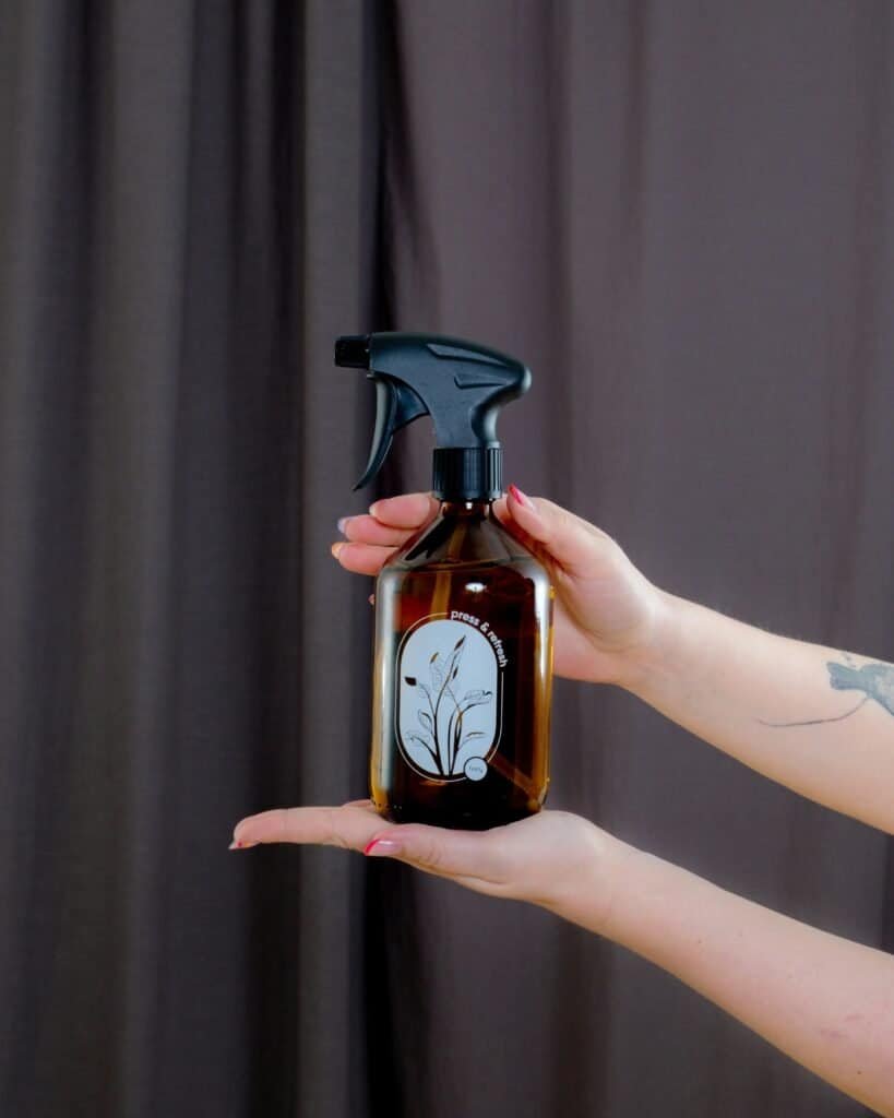 Eco-friendly cleaning spray in amber glass bottle with plant design.