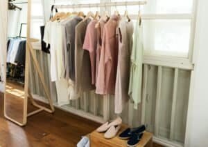 Organized clothing rack with pastel and neutral-toned casual wear in a bright, minimalist room.