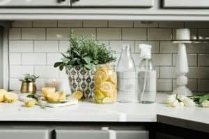 Natural cleaning supplies with lemon and herbs on a kitchen countertop.