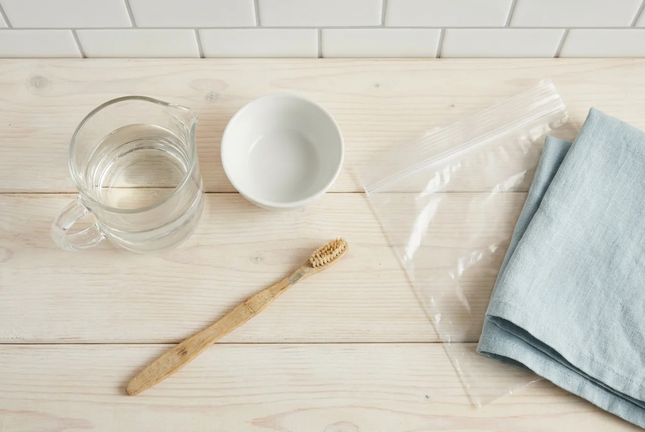 Shower head cleaning supplies: white vinegar, a bowl, an old toothbrush, and a plastic bag